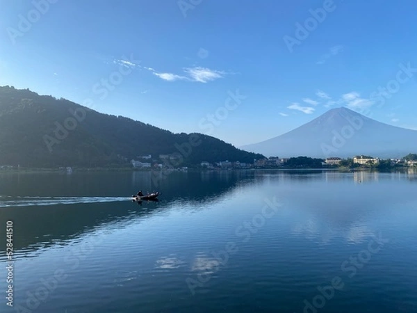 Fototapeta Boat ride across the lake Kawaguchiko with beautiful clear Mt. Fuji view, sunny day with blue sky and the clear tip of the mountain, year 2022 August 27th, 6:27am Yamanashi prefecture, Japan
