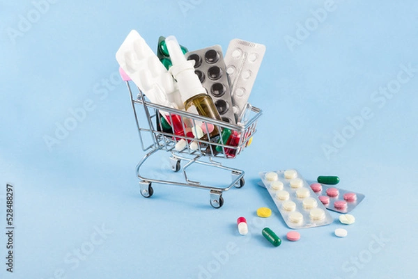 Fototapeta on a blue background a cart with medicines with copy space