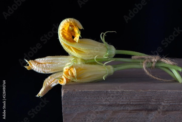 Obraz yellow flowers zucchini vegetables on a wooden table