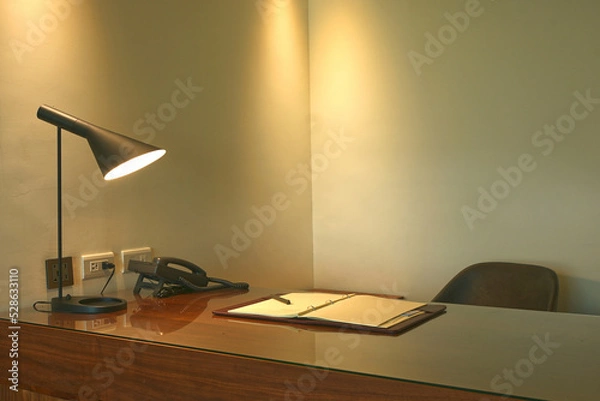 Obraz Lamp, phone and note book on a desk in a luxury office