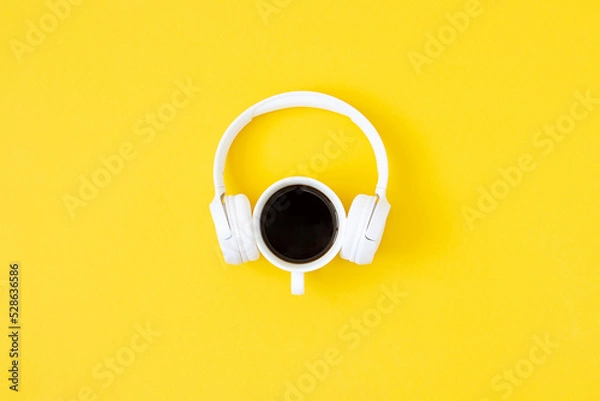 Obraz A cup of black coffee and white headphones on yellow background. Minimal style, Flat lay, Top view. Education concept
