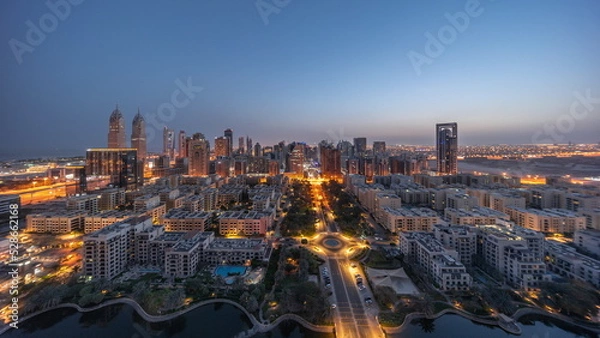 Obraz Panorama of skyscrapers in Barsha Heights district and low rise buildings in Greens district aerial night to day timelapse.