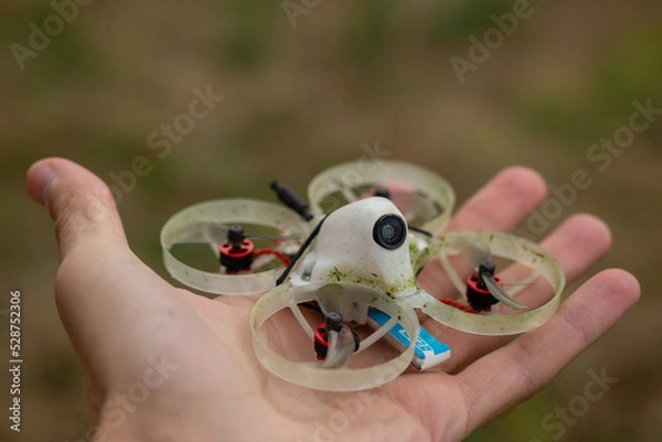 Fototapeta Mini FPV drone in the palm of hand. Small quadcopter with protection for indoor flights,