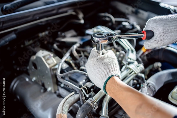 Fototapeta close up of view Auto mechanic repairman using a socket wrench working engine repair in the garage, change spare part, check the mileage of the car, checking and maintenance service concept.