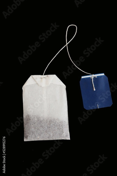 Fototapeta Rectangular tea bag with blue label isolated on black. Mockup, detail for creating marketing compositions in the theme of tea party, food products