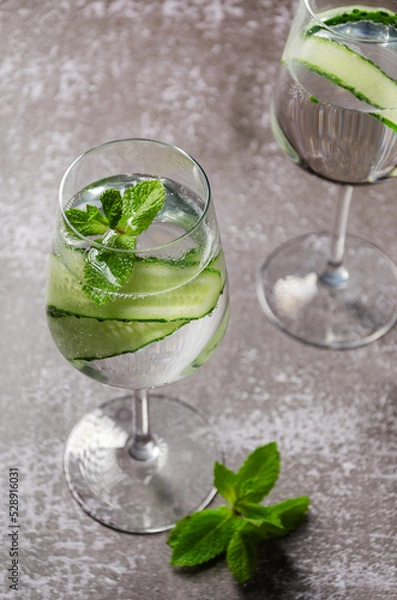 Obraz Classic Gin and tonic with cucumber or Tom Collins or Gin Fizz alcoholic cocktail with Gin, tonic, ice, cucumber and mint or mocktail on a grey background