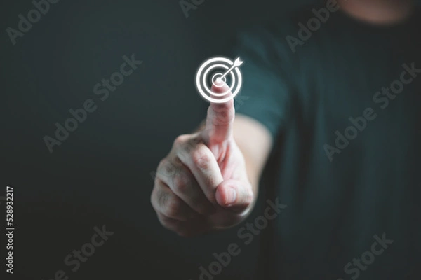 Fototapeta Businessman hand touching target dartboard to setup goal and achievement objectives for business investment. Business financial and startup concept.