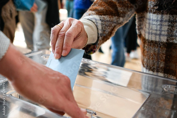 Fototapeta Illustration picture shows a person voting with a ballot paper in its envelope just before being placed in the ballot box