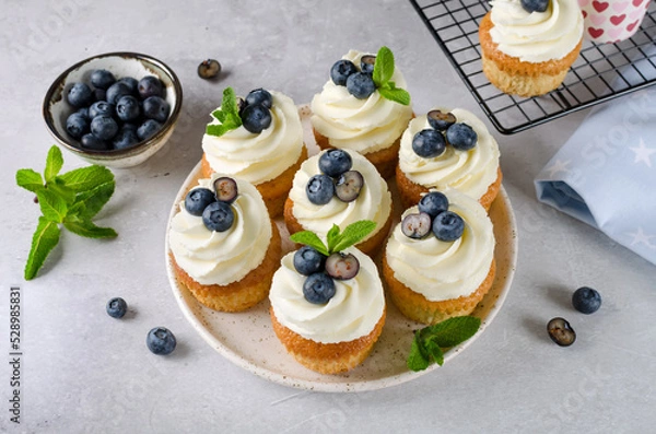 Fototapeta Vanilla cupcakes with blueberries and with cream cheese frosting
