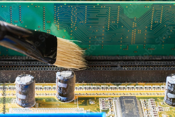 Obraz Brush cleaning an old motherboard from covering dust and dirt. Close-up.