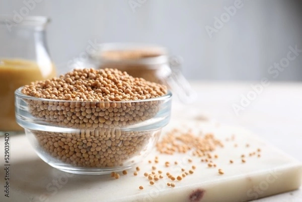 Fototapeta Mustard seeds in glass bowl on board. Space for text