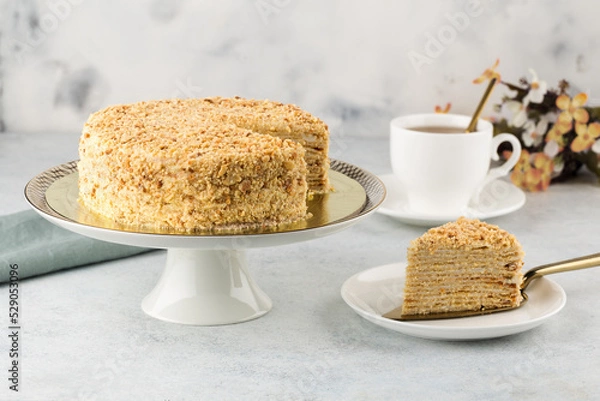 Fototapeta Sliced Napoleon cake on cake stand on white concrete background