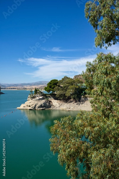 Fototapeta Spectacular panoramic views of the Guadalhorce reservoir, next to the Caminito del Rey in Malaga, Spain. Turquoise blue water and forest with blue sky on a sunny day.