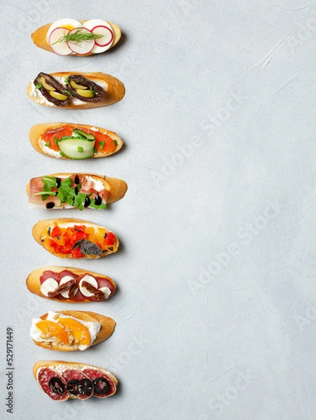 Obraz Brushetta, antipasti  or authentic traditional spanish tapas set on background. Variety of  pinchos (pintxos) in a bar or restaurant or home party or picnic. Flat lay, top view, copy space for text