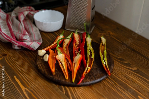Fototapeta cut pods of red hot pepper on a wooden board