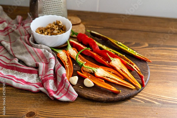 Fototapeta cut pods of red hot pepper on a wooden board