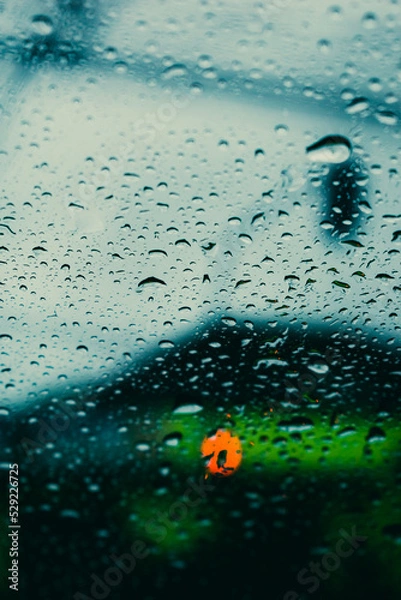 Fototapeta parabrisas con gotas de lluvia con luz de semáforo desenfocado en día nublado