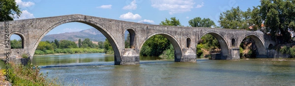 Fototapeta The Bridge of Arta. A stone bridge that crosses the Arachthos river  in the west of the city of Arta in Greece. Sunny day with blue sky