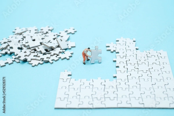 Obraz 水色背景に白いパズルを組み立てる一人の作業員のフィギア