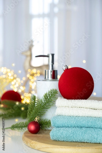 Obraz Stack of blue and white towels folded on the table, fir branches, Christmas balls and Christmas lights. SPA massage or beauty salon, relaxation and wellness in Christmas or New Year variant.