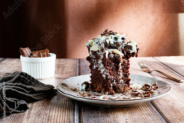 Fototapeta Piece of chocolate american pie with condensed milk icing, medal flakes and grated chocolate on top, brown tones, appetizing sweet dessert