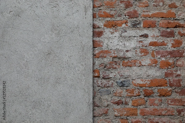 Fototapeta Half red brick wall and half  grey stone wall,  rough surface with uneven bricklayer, space for text
