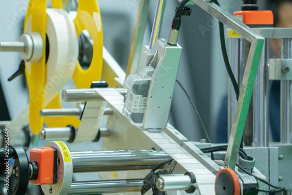 Fototapeta Label printing machine with Roll sticker printing working in a packaging line production in a factory. Automatic label printing system in an automation system in an industrial factory.