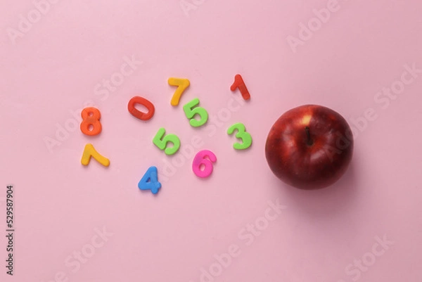 Fototapeta Education concept. Apple and colored numbers on a pink background. top view