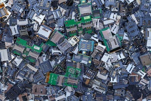 Fototapeta Many SIM card tray backgrounds and SD card trays are prepared for mobile phone repair parts in Top View and Copy Space for messages. Electronic waste that can be used to extract precious metals