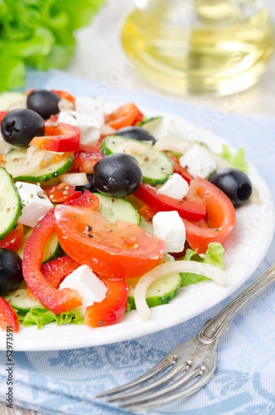 Obraz Greek salad with feta cheese, olives and vegetables, closeup