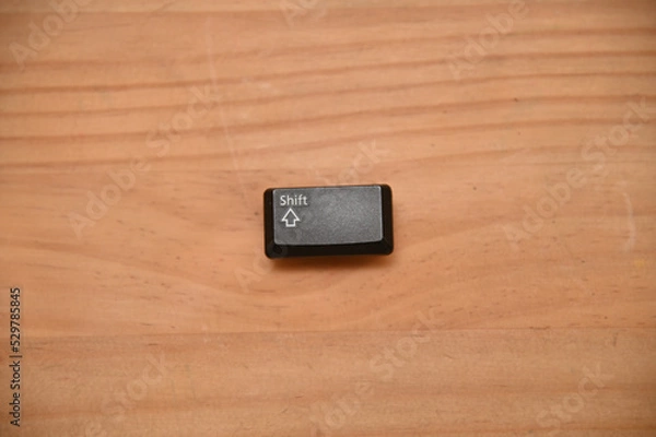 Fototapeta 木目のテーブルの上に置かれたシフトキーのキートップ１つ