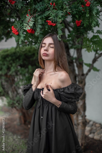 Fototapeta portrait of a beautiful girl on the background of a tree with flowers