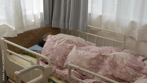 Obraz 介護用ベッドで眠る高齢者女性（中）
