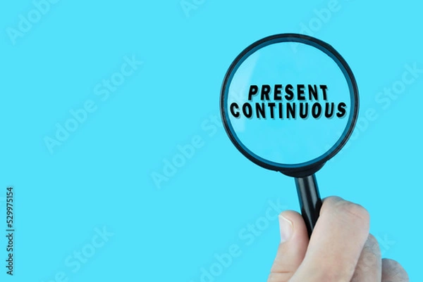Fototapeta Focused on learning English language. Basic English tenses. Present continuous under magnifying glass. Grammar content for teacher and student.