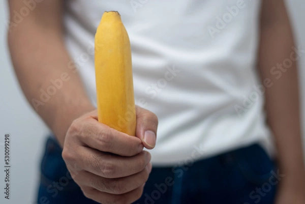 Obraz Man holding a banana (penis concept)