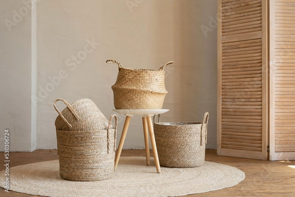 Fototapeta Various wicker baskets for interior decoration stand on the floor in a modern living room.