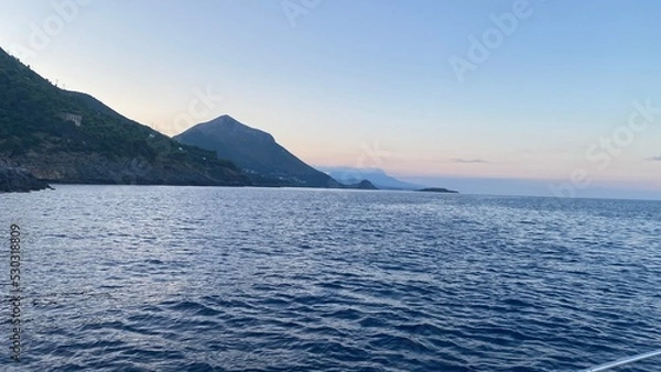 Fototapeta Landscape of the south of Italy from a boat at sunset with high hills, sea till the line of the horizon with past colour in a sunny day