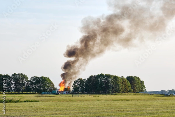 Fototapeta Large fire on the horizon of an agricultural field with a huge pillar of smoke in de sky. Fire near Hallum Friesland in The Netherlands