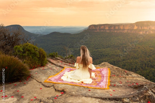 Obraz Woman on rug on mountain cliff with vsplendid iews