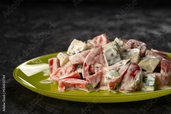Fototapeta close-up shot of salad with tomatoes and cucumbers on black
