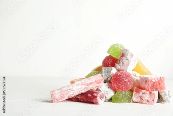 Fototapeta Delicious colorful candies on white table. Space for text