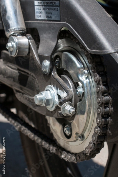 Fototapeta Detail of a motorcycle wheel, swingarm, sprocket and rear drive chain transmitting engine power