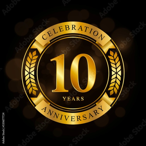 Fototapeta 10 Year Anniversary celebration template design, with shiny ring and gold ribbon, laurel wreath isolated on black background, logo vector