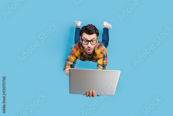 Obraz Full size portrait of craze geek man falling hands hold use netbook isolated on blue color background