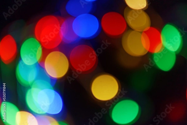 Fototapeta Defocused bokeh lights on black background, an abstract naturally blurred backdrop for Christmas eve or birthday party. Festive light texture. Colorful garland in blur. Overlay effect for design. 2023