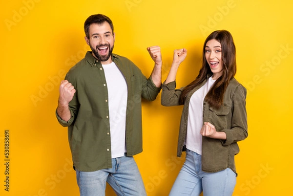 Obraz Photo of two delighted overjoyed people raise fists celebrate luck isolated on yellow color background