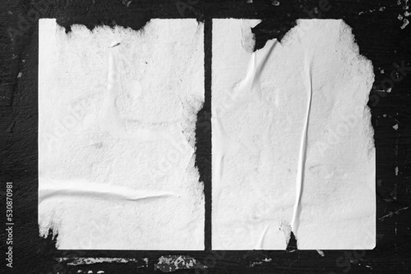 Fototapeta Two sheets of paper taped to a black wall.