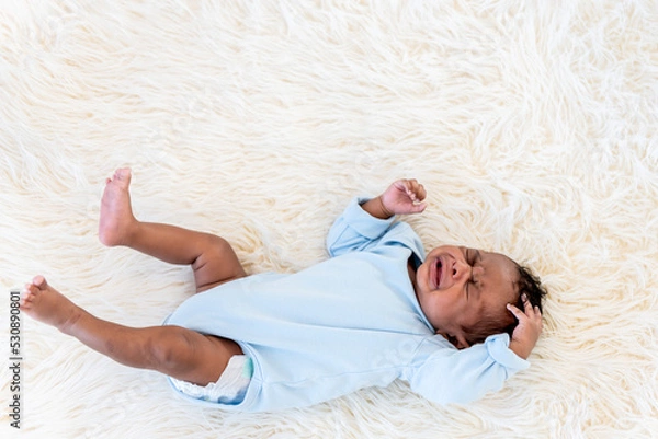 Fototapeta Portrait images of half Nigeria half Thai, 1-month-old baby newborn son, lying on a white bed and is crying, to infant and family concept.