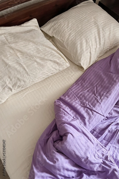 Fototapeta Aesthetic minimalistic bedroom interior design. A bed with a white sheet and pillows, a rumpled lilac blanket
