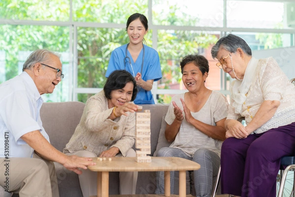 Obraz Dementia therapy in playful way. Group of senior elder people stay at nursing home, enjoy activity.relation playing Jenga or tumbling tower wood block game. Training fingers and fine skills